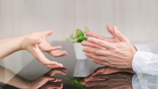 対面して座っている男女の手元