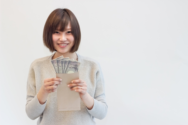 1万円札の入った封筒を手にしてこちらを向いている笑顔の女性
