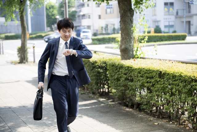 腕時計を見ながら急いでいる男性