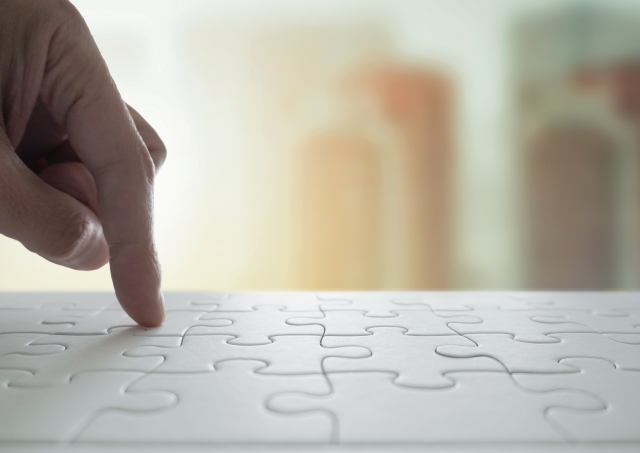 完成したジグソーパズルと人の指先