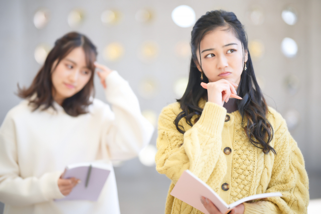 顎の下に手を置いて考えている様子の女性