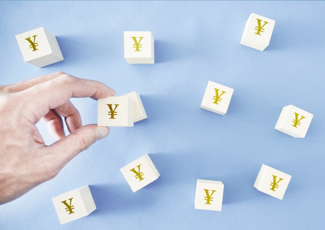 円マークが印字されたたくさんの木製のブロックをひとつ持ち上げている人の手元