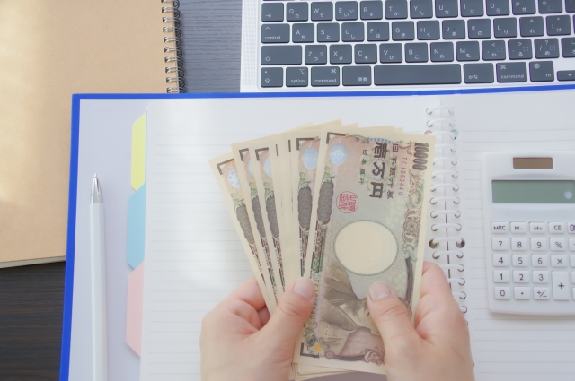 複数枚の1万円札を両手で持っている人の手元