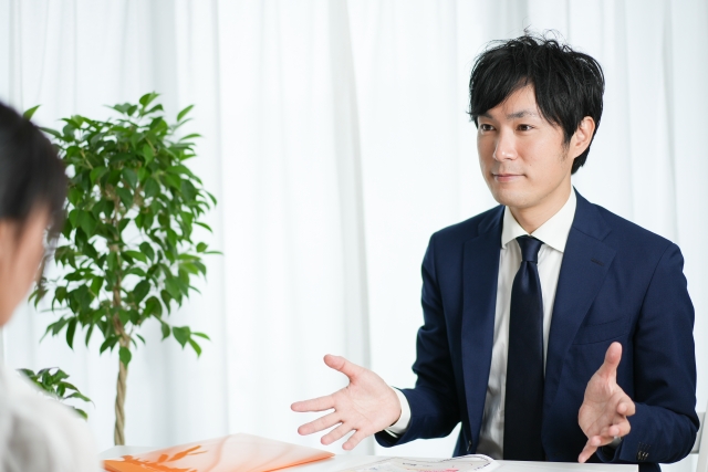 対面している人に説明しているスーツ姿の男性