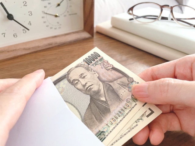 封筒から3枚の1万円札を取り出している人の手元