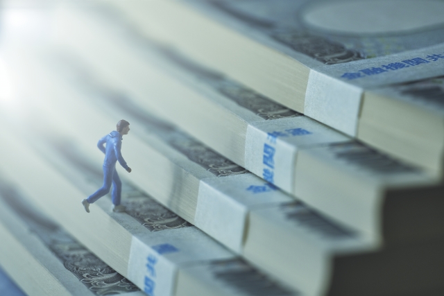 札束で作られた階段を上っているミニチュアの男性