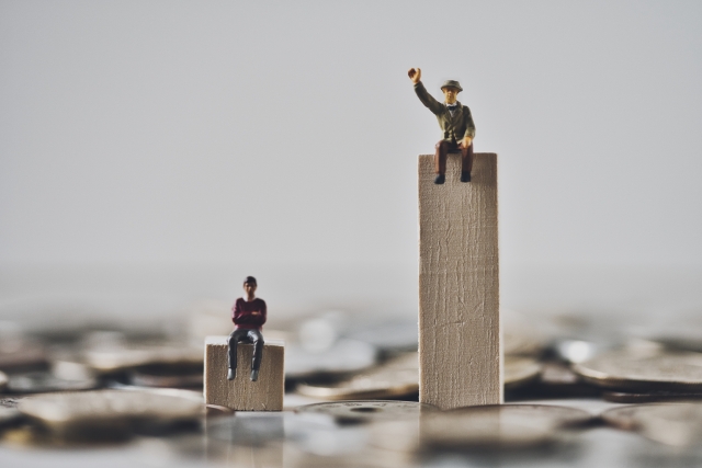 2つの木製ブロックの上にそれぞれ座っているミニチュアの男性