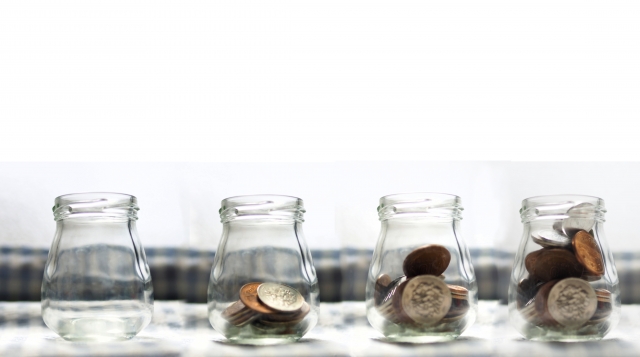 4つ並んだガラス瓶の中に入っている小銭