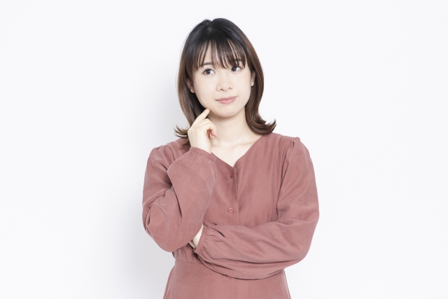 人さし指を顎の下に置いて何かを考えている様子の女性