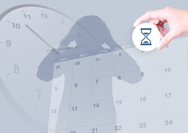 頭を抱える人のシルエットと砂時計のアイコン