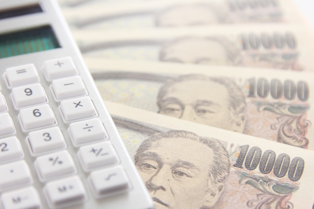複数枚の１万円札の上に置かれた電卓