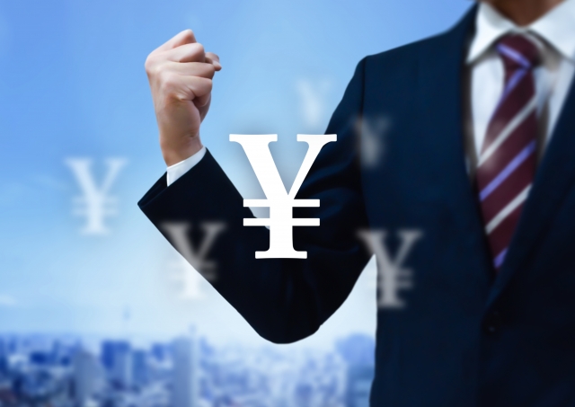 ガッツポーズをしているスーツ姿の男性と円マーク