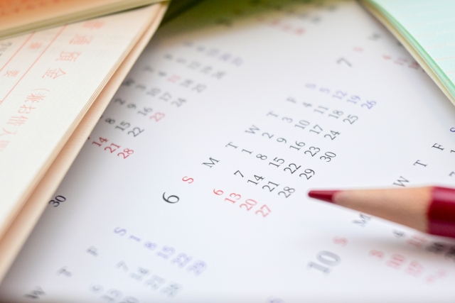 重なった通帳とカレンダーの上に置かれた赤鉛筆