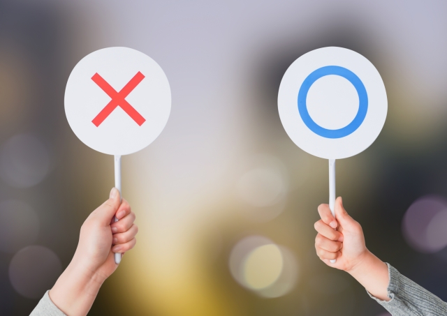 〇と×のプレートを持っている人の手元