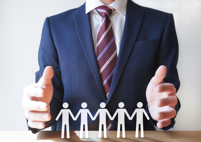 5枚繋がった人型の切り絵とスーツ姿の男性