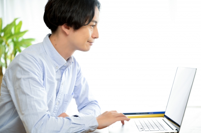 ノートパソコンを操作している笑顔の男性