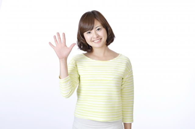 右手で5のサインを出している笑顔の女性