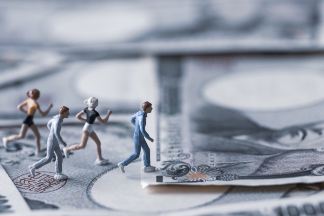 1万円札の上を走っている4体のミニチュア