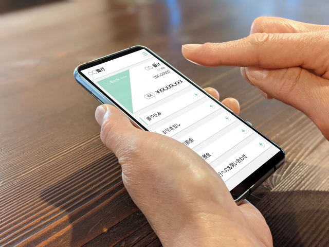 スマホで銀行のアプリを操作する人の手元