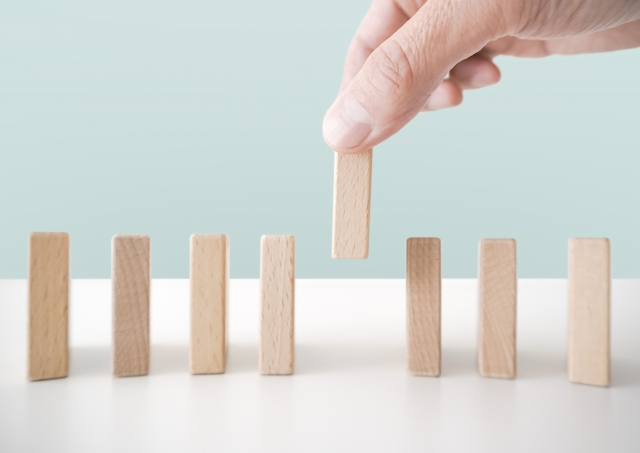 木製のドミノ牌を並べている人の指先