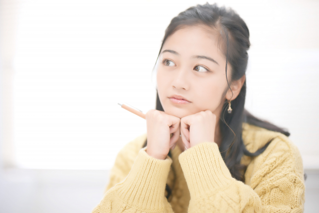顎の下に手を置いて悩んでいる女性