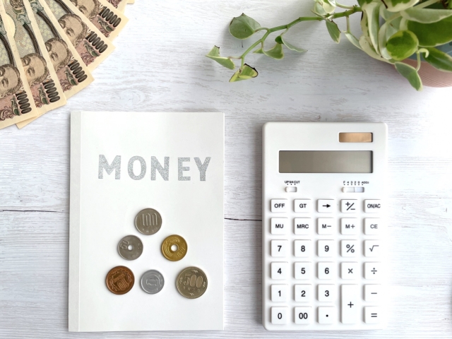 電卓と家計簿の上に並んだ小銭