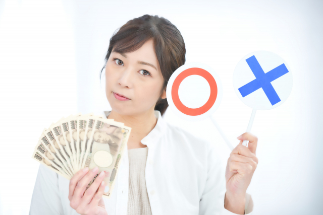 お札とマルバツプレートを持つ女性