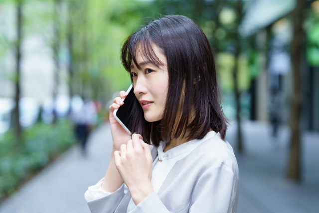 困った表情で電話をしている女性