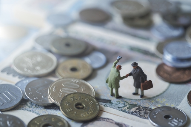 お札の上で握手をしている2人のミニチュアの男性