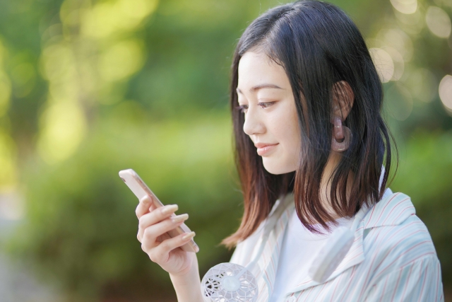 手に持ったスマホの操作をする笑顔の女性