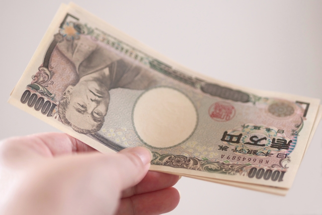 何枚かの1万円札を差し出している人の手元