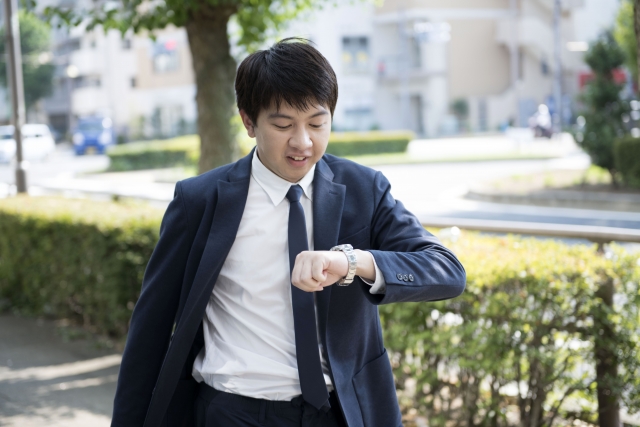 腕時計を見ながら歩いている男性