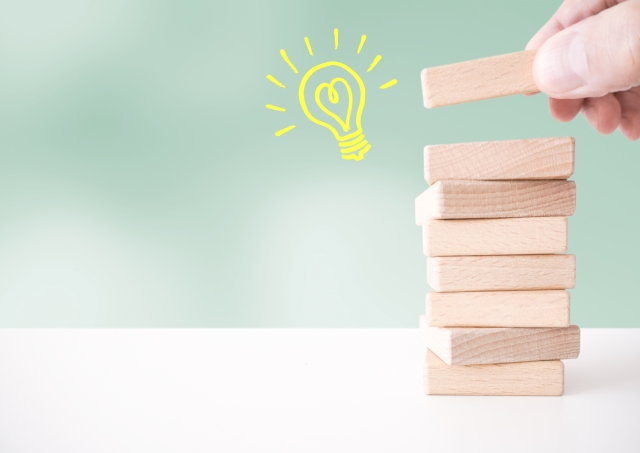 積み木を重ねる手元と電球マーク