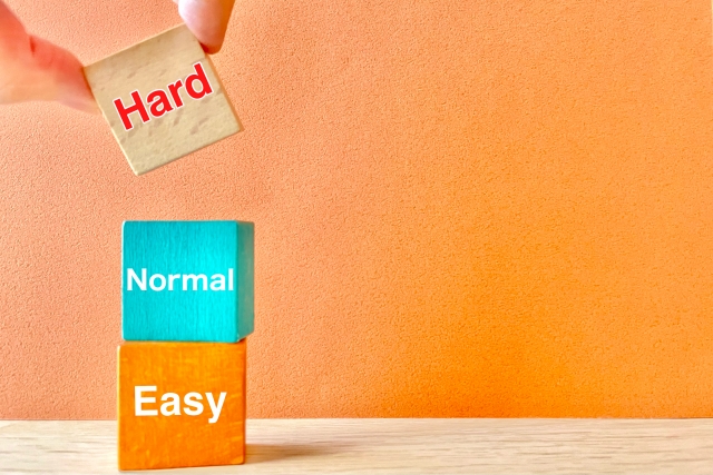 EasyとNormalとHardと印字されたブロックを積み上げる人の指先