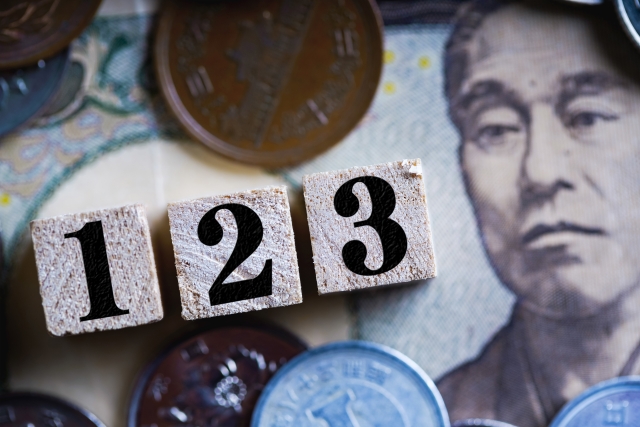 １万円札の上に並べられた小銭と1から3までの数字のブロック