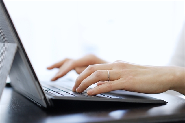ノートパソコンのキーボードをタイピングしている女性の手元