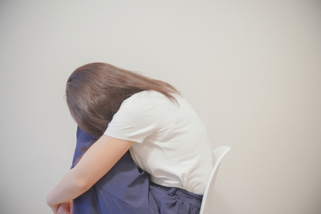 椅子に座って膝を抱える女性
