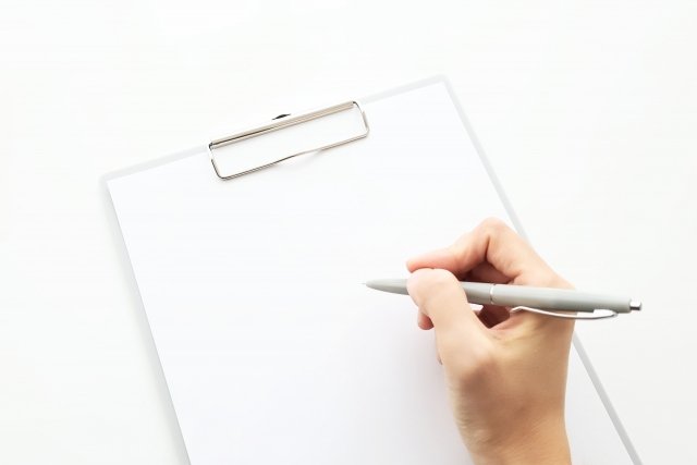 クリップボードの書類に書き込もうとしている手元