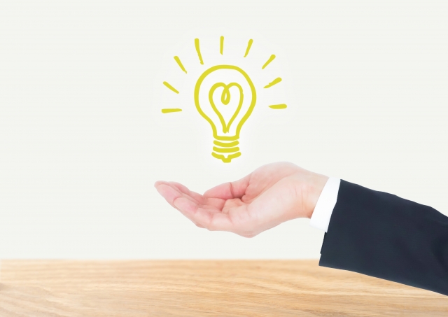 ビジネスマンの手のひらに浮かんでいる電球マーク