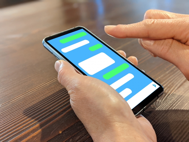 スマホでチャットをしている人の手元