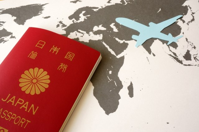 世界地図の上に置かれた赤いパスポート