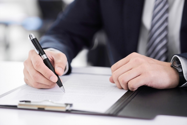 書類に書き込みをしている男性の手元