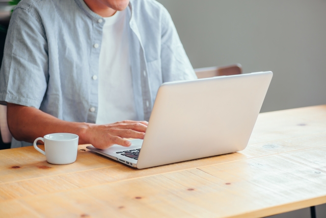 座ってノートパソコンを操作している男性