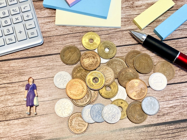テーブルの上に並べられた小銭と女性のミニチュア
