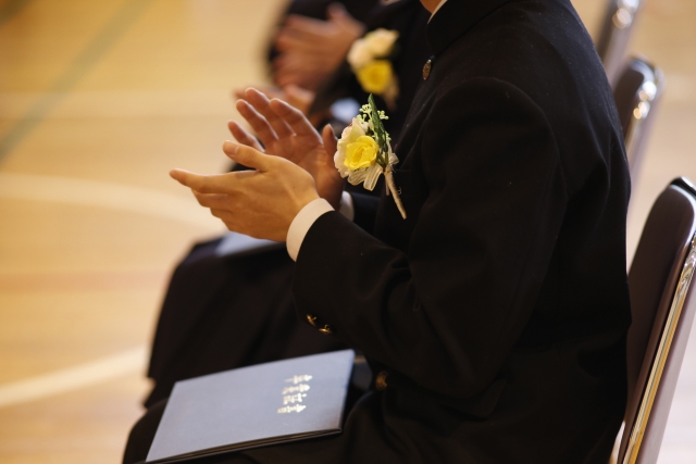 卒業式で拍手をしている卒業生