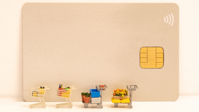 クレジットカードの前に並んでいるショッピングカートのミニチュア