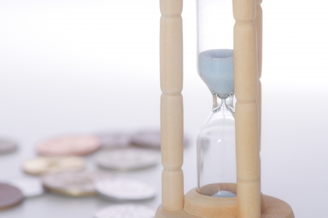 数枚の硬貨と砂時計
