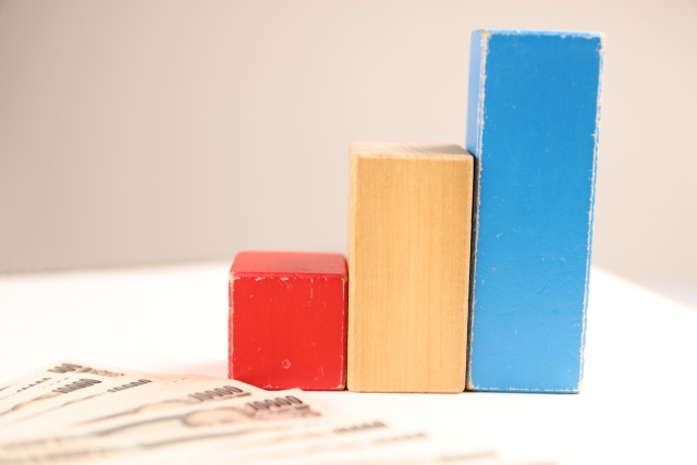 手前に並べられた数枚の1万円札と木製のブロック