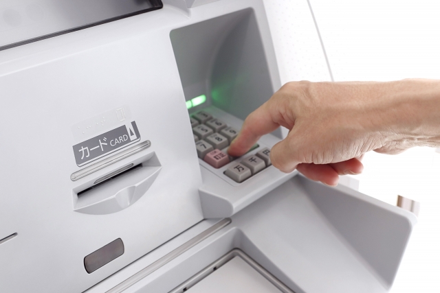 コンビニATMのテンキーを操作をしている人の手元