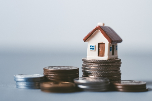 積み上げられた小銭の上に置かれたミニチュアの家